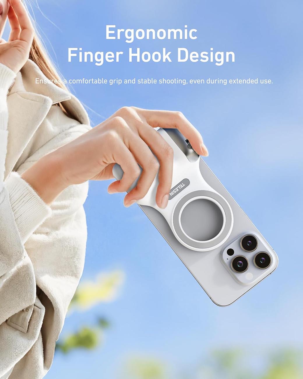 Hand holding a phone case with ergonomic finger hook design against a blurred outdoor background